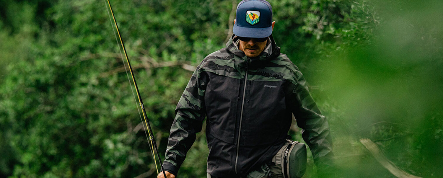 An angler walking with his fishing pole near a river